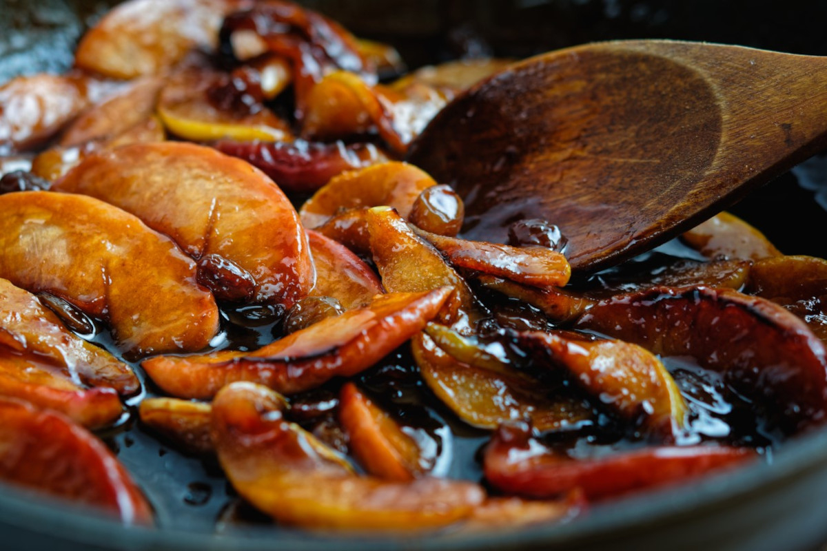 A skillet with peaches cooking in a sauce