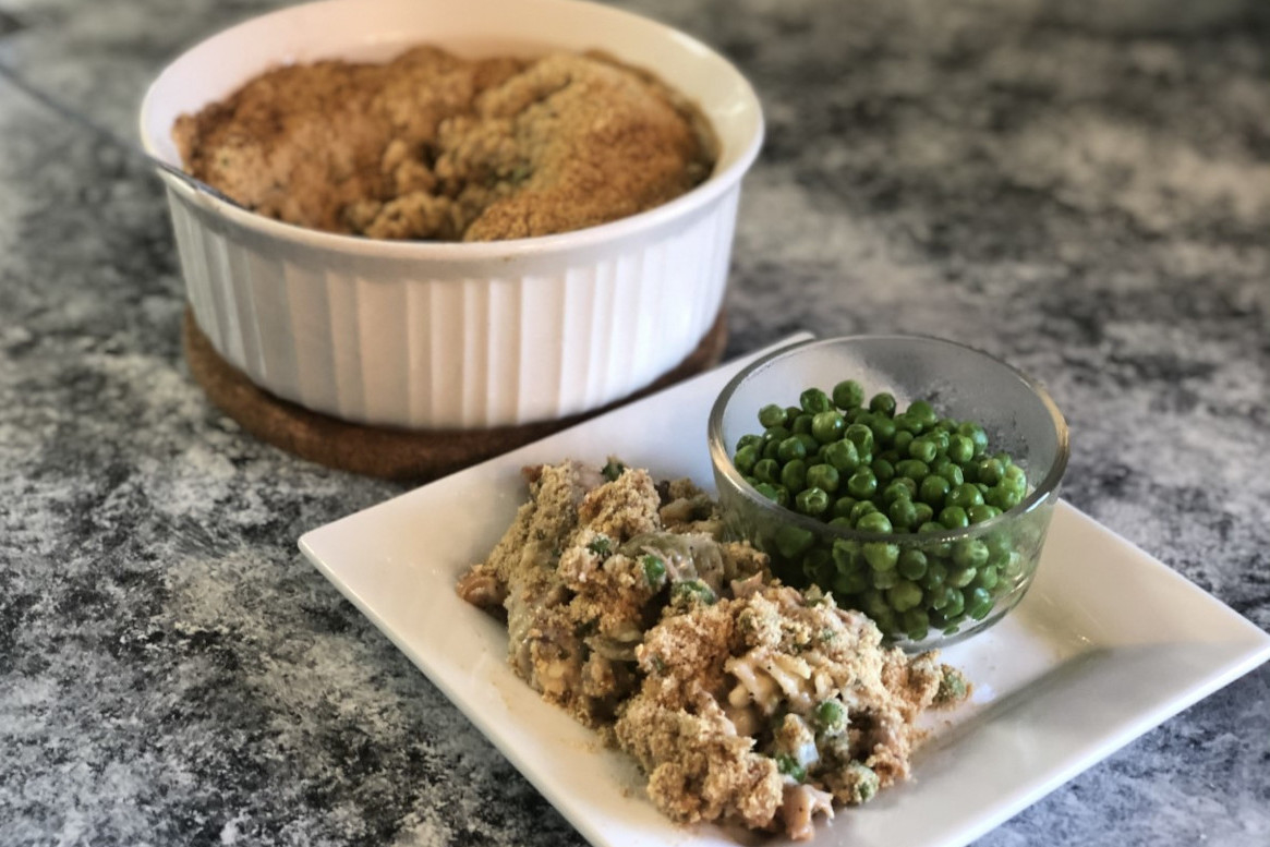 A plate with tuna noodle casserole and a small bowl of peas